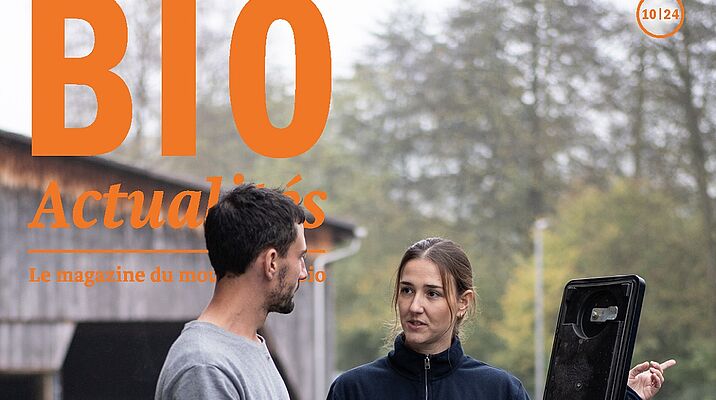 Page de couverture du Bioactualités 10|24: Un homme et une femme se parlent, ils sont devant une machine agricole.