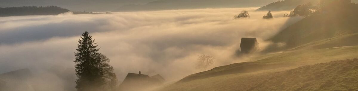 Berge, Landschaft und Almhütten im Wolkenmeer. 