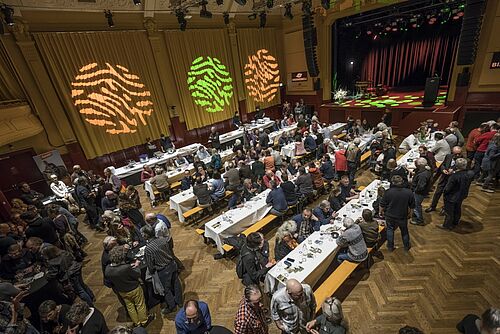 [Translate to Französisch:] Ein gut besetzter Festsaal von oben.