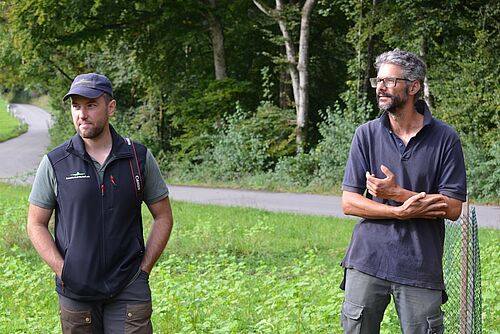 Deux hommes se tiennent sur une pelouse et donnent des conférences. . 