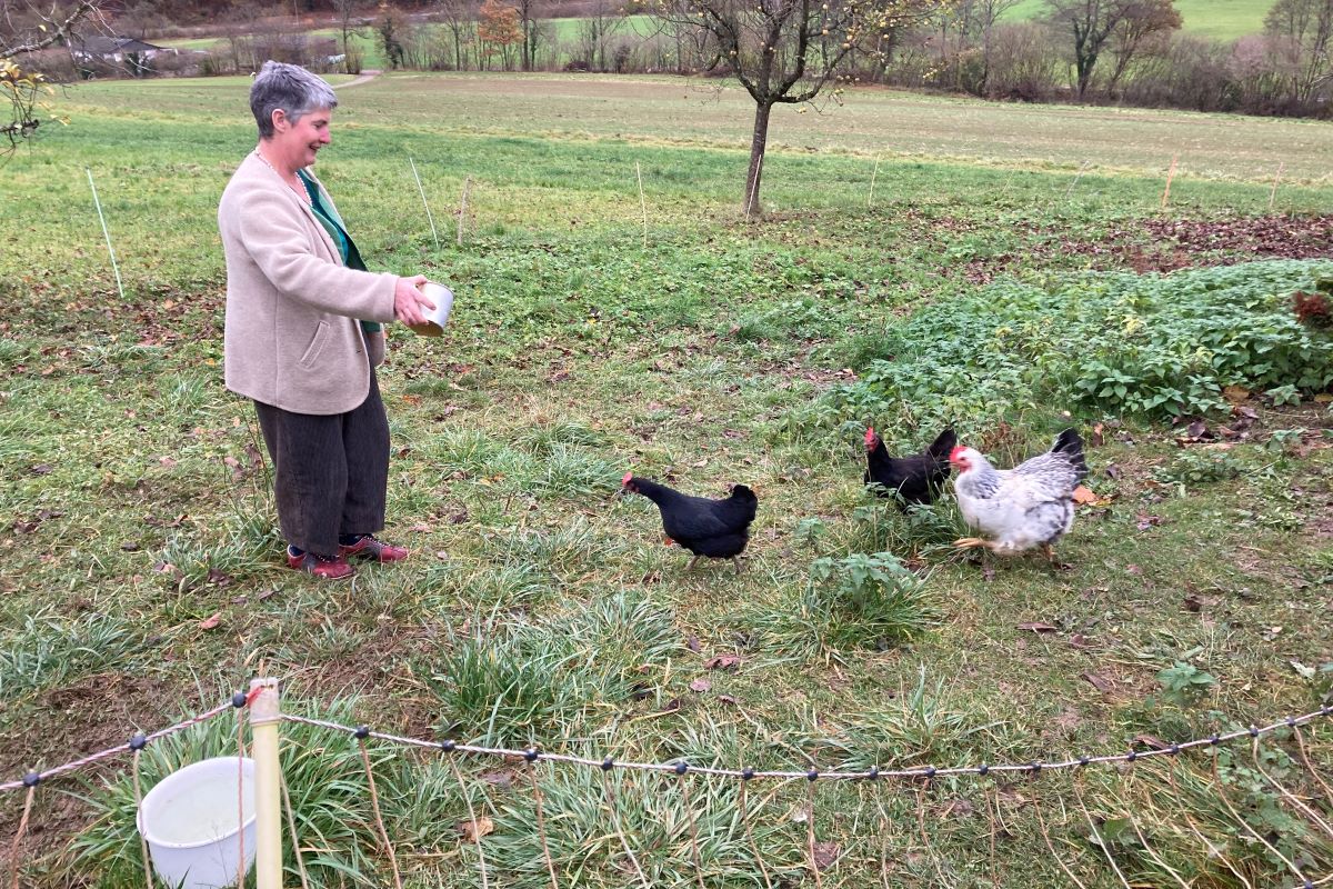 La protagoniste donne à manger aux poules dans un pré